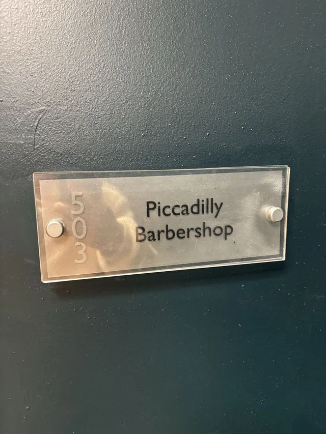 The Piccadilly Barbershop sign on the door of Room 503
